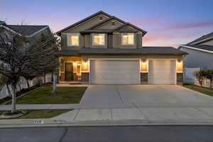 View of front of property featuring brick siding, driveway, stucco siding, and an attached garage