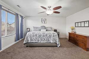 Carpeted bedroom with ceiling fan and baseboards