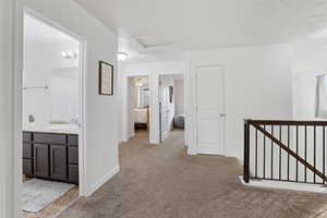 Corridor featuring an upstairs landing and light colored carpet