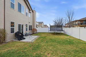 Fenced backyard with a patio, a trampoline, and a residential view