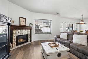 Living room featuring dark wood finished floors and a stone fireplace