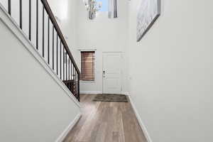 Foyer with light wood-style flooring, a high ceiling, and a chandelier