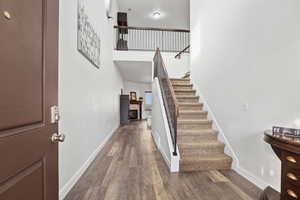 Staircase featuring a high ceiling, wood finished floors, and a fireplace