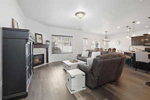 Living area featuring a stone fireplace, dark wood-style flooring, and recessed lighting