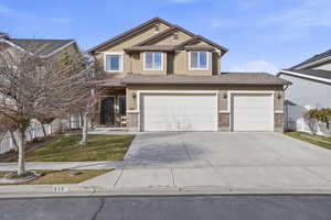 View of front of house featuring stucco siding, a porch, concrete driveway, and brick siding