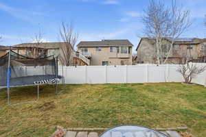 Fenced backyard featuring a residential view and a trampoline
