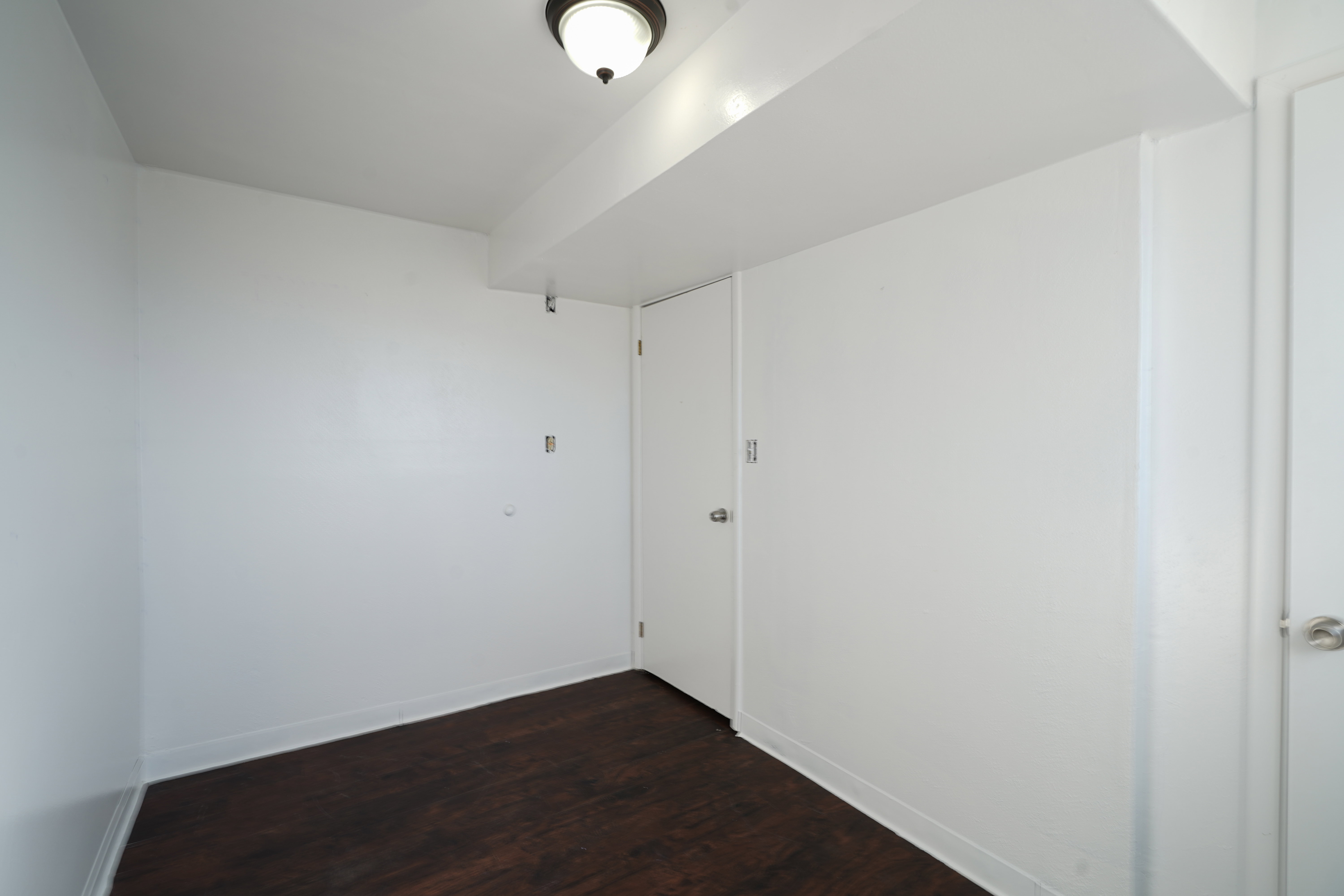 Empty room featuring dark wood-type flooring and baseboards