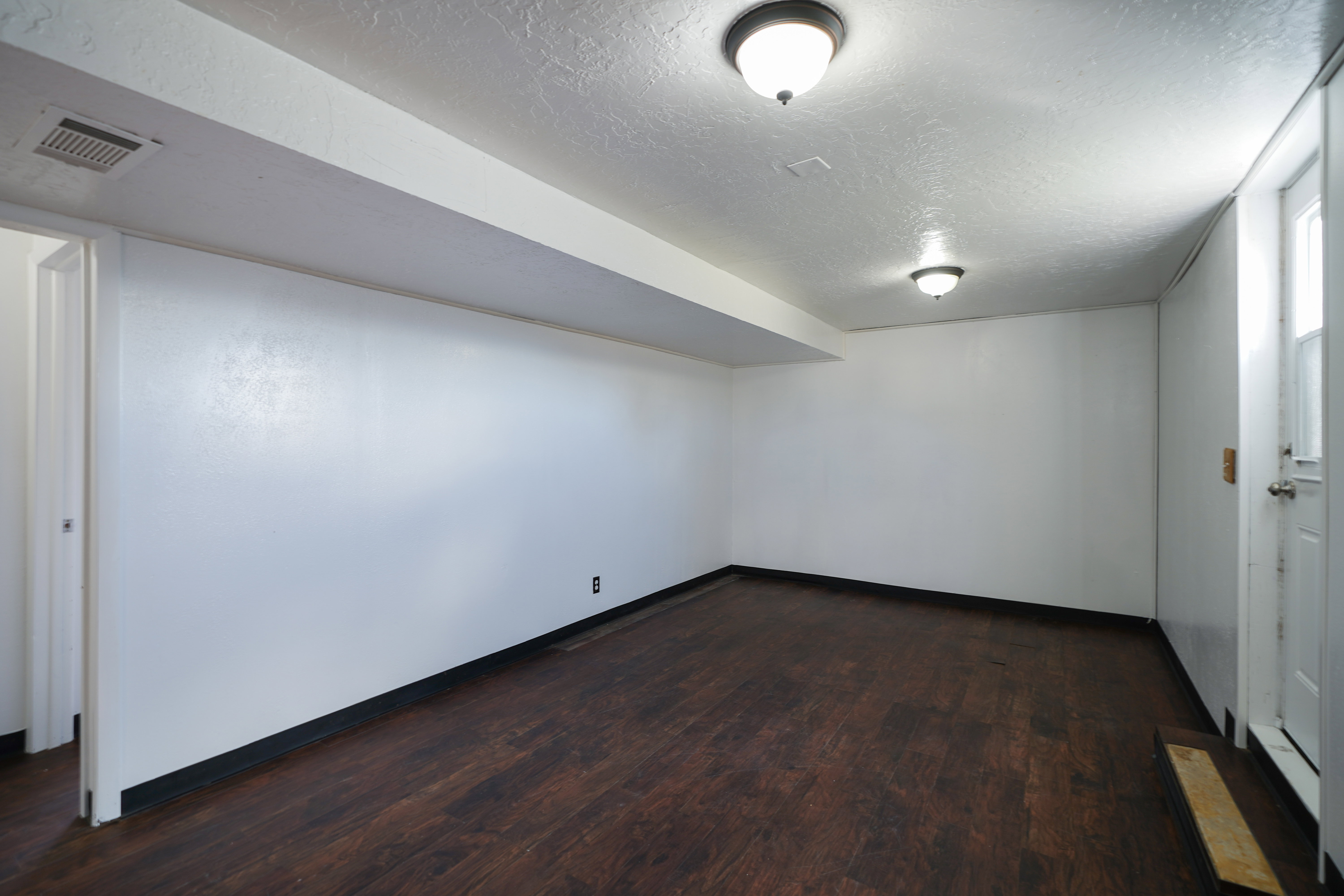 Finished basement with dark wood-style flooring and a textured ceiling