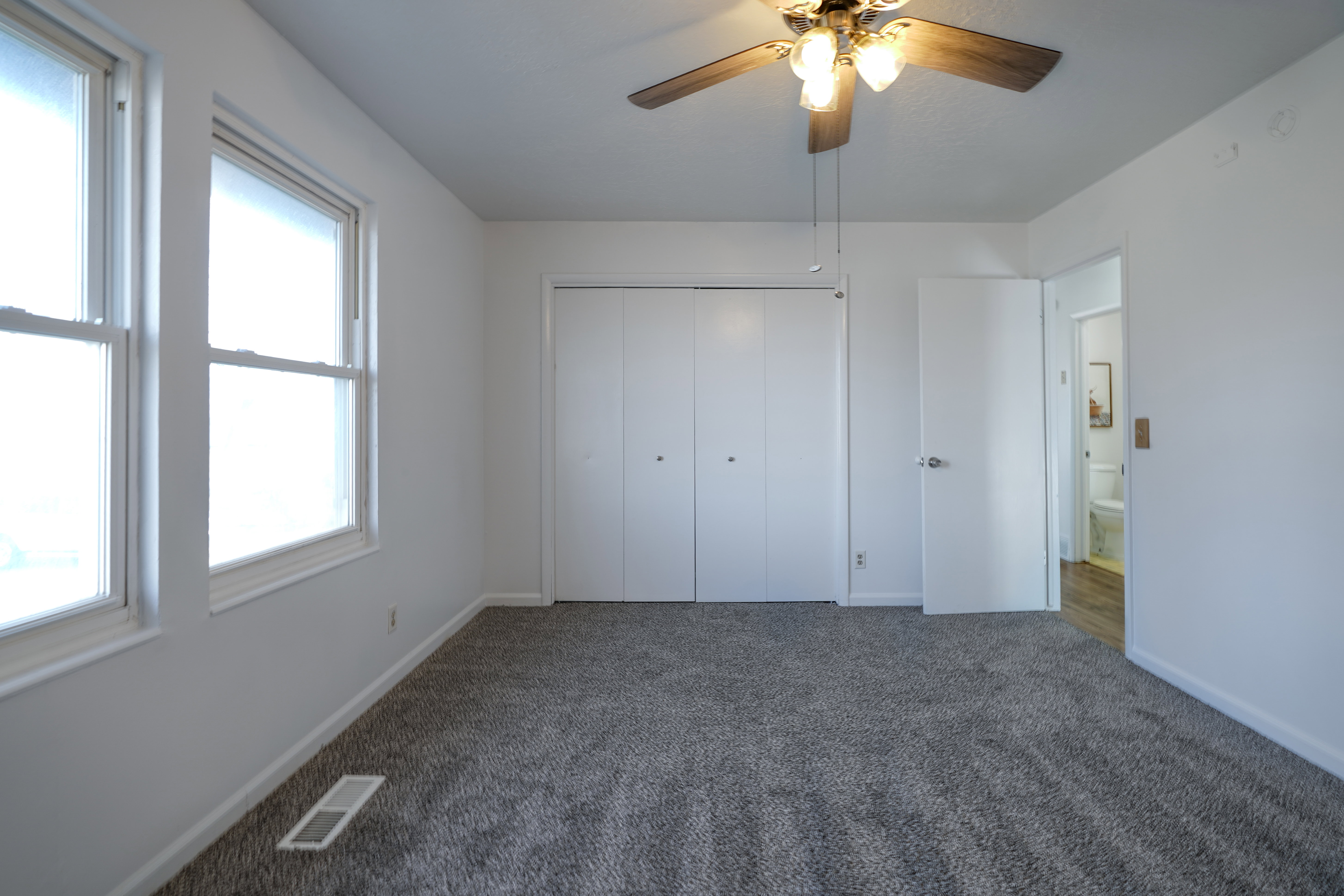 Unfurnished bedroom with dark carpet, a closet, and ceiling fan