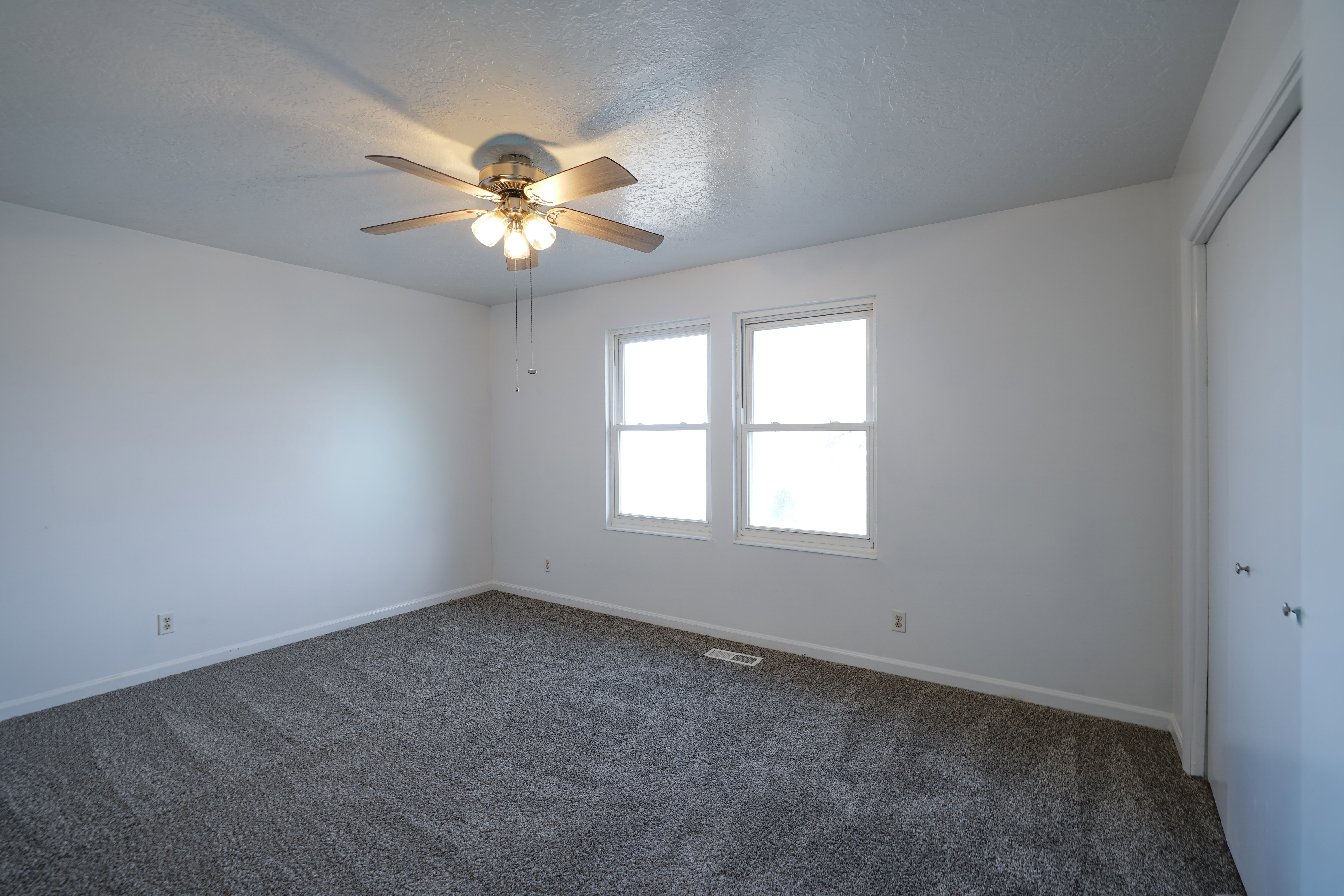 Unfurnished bedroom with dark carpet, a closet, a ceiling fan, and a textured ceiling