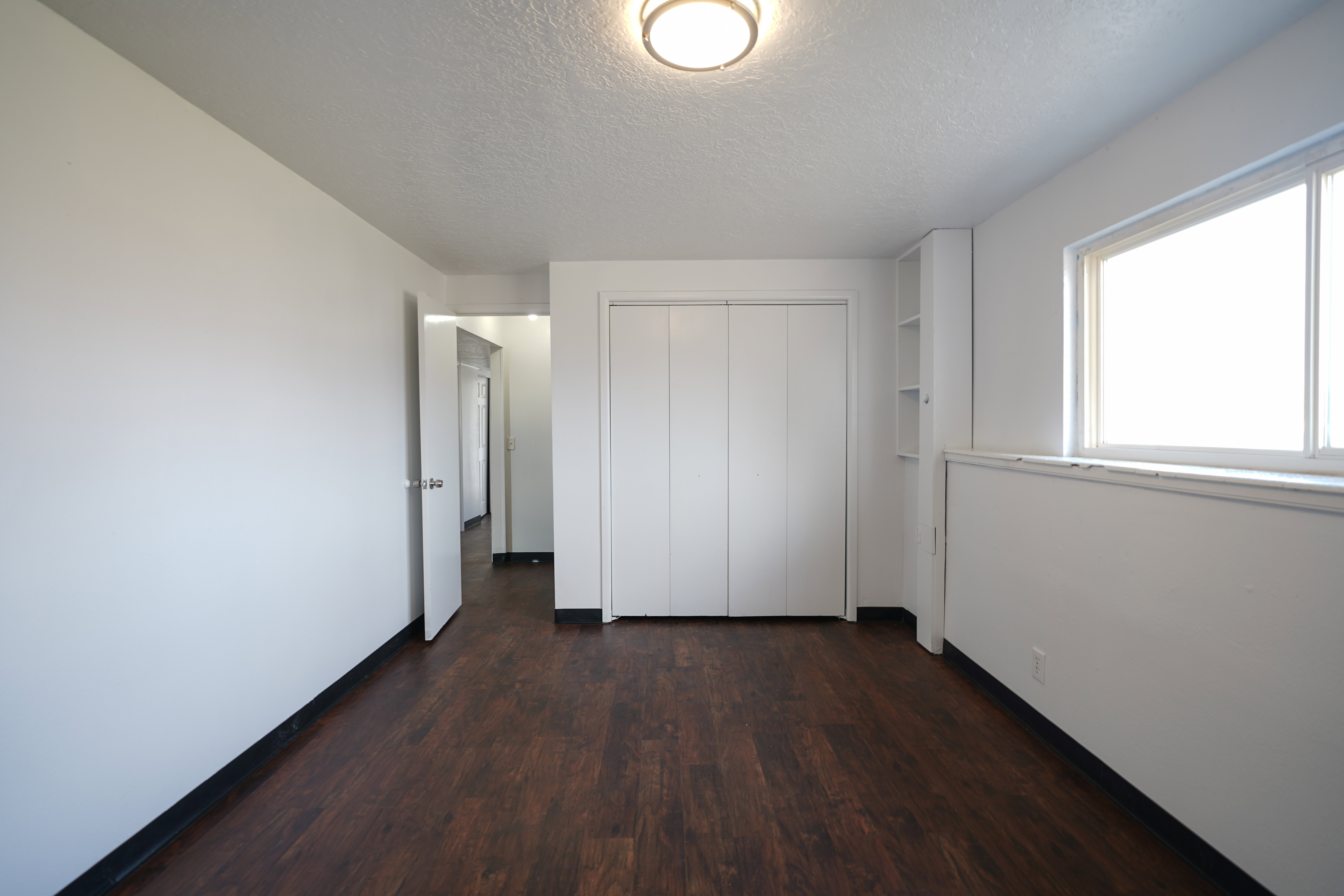 Unfurnished bedroom with dark wood-style flooring, a textured ceiling, and a closet