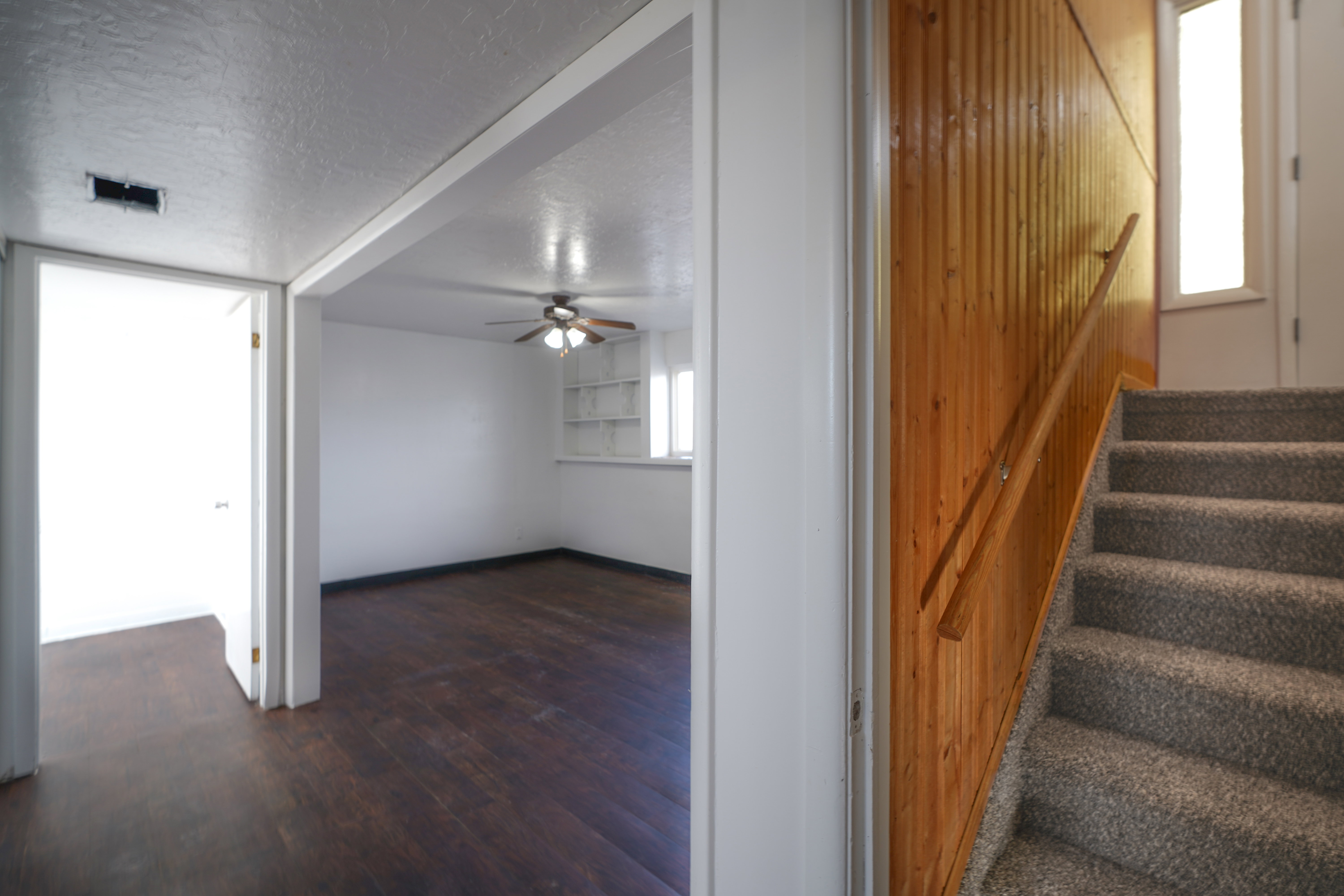 Staircase with a textured ceiling, hardwood / wood-style flooring, and ceiling fan