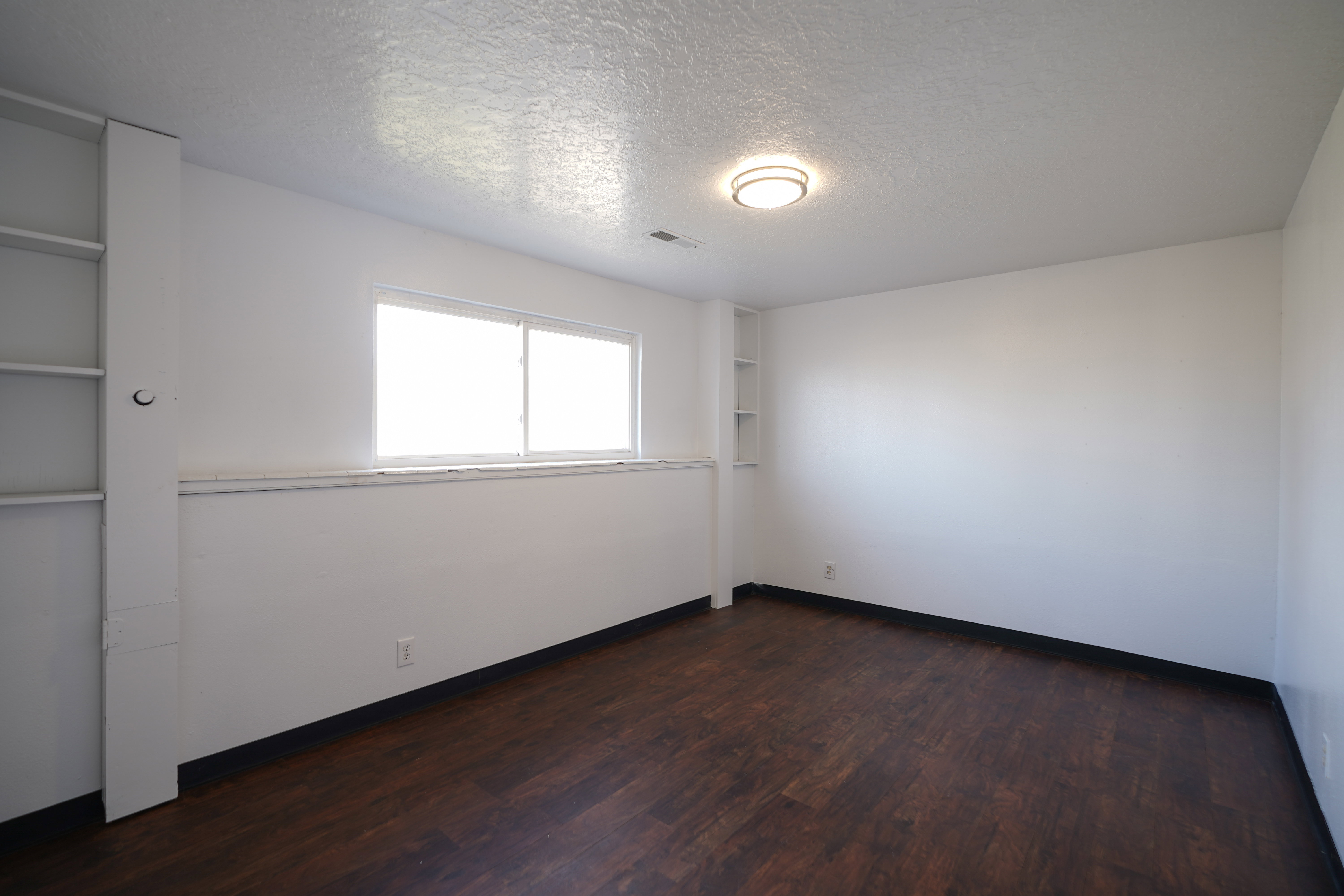Spare room with a textured ceiling and dark wood-style floors