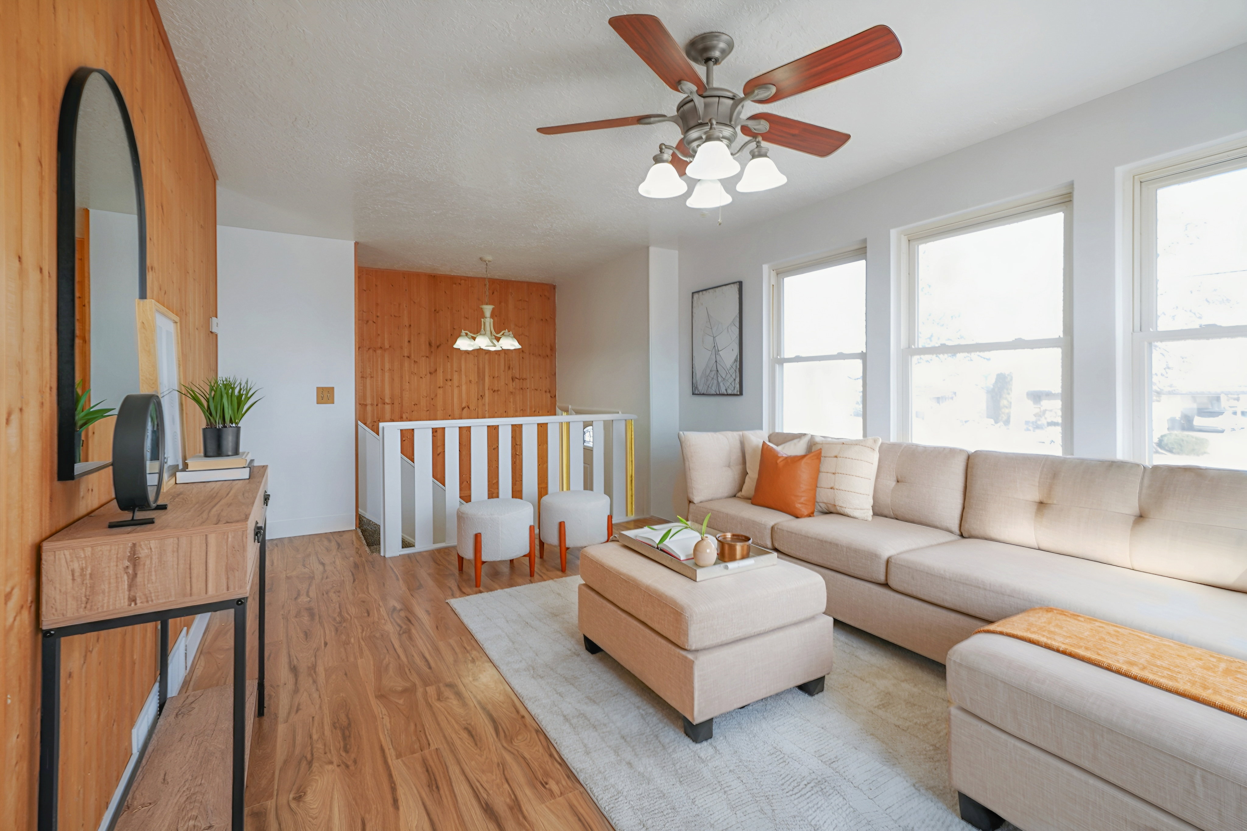 Living room featuring a chandelier, light wood-style floors, a ceiling fan, wood walls, and a textured ceiling