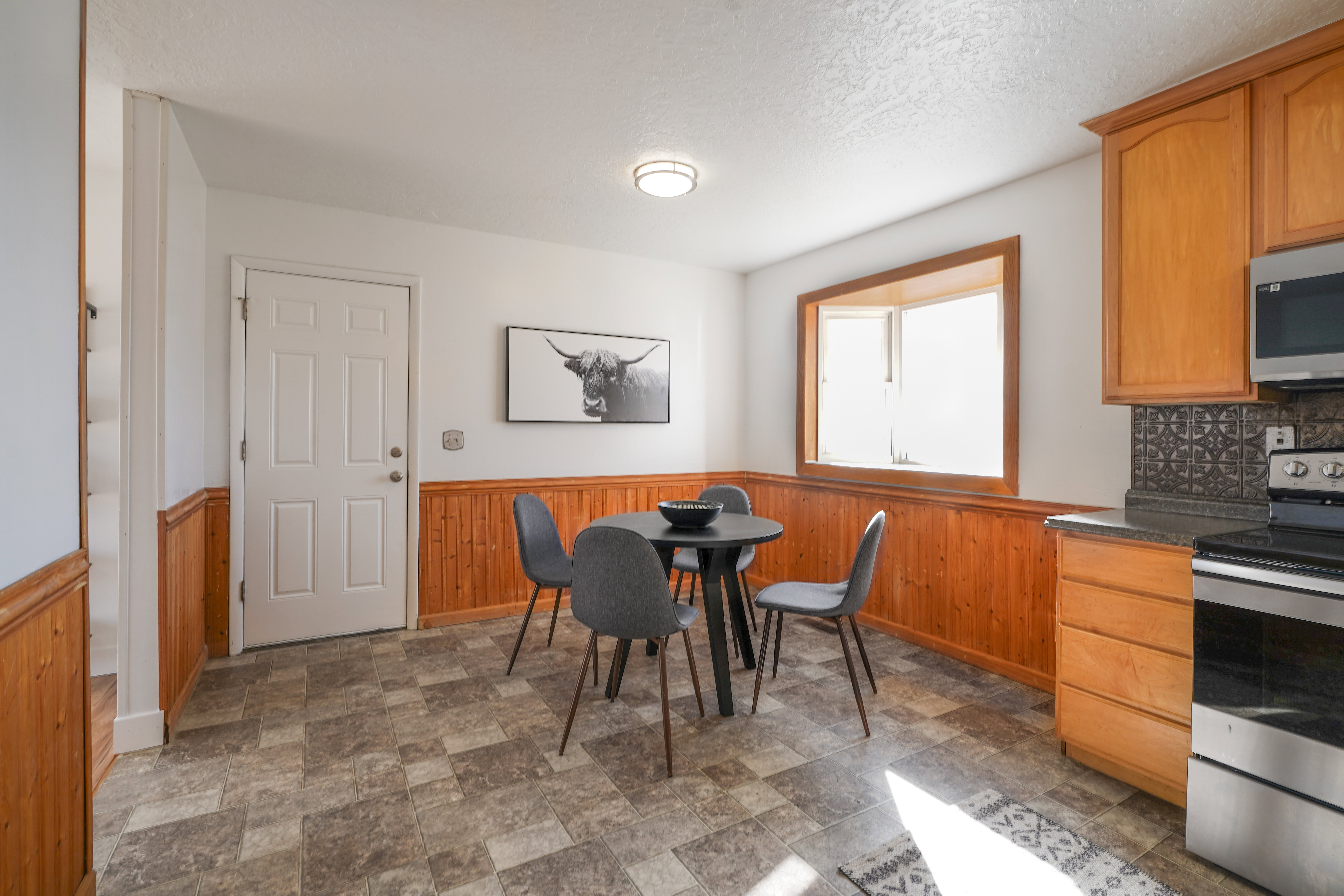 Dining area with a wainscoted wall, wood walls, stone finish floors, and a textured ceiling