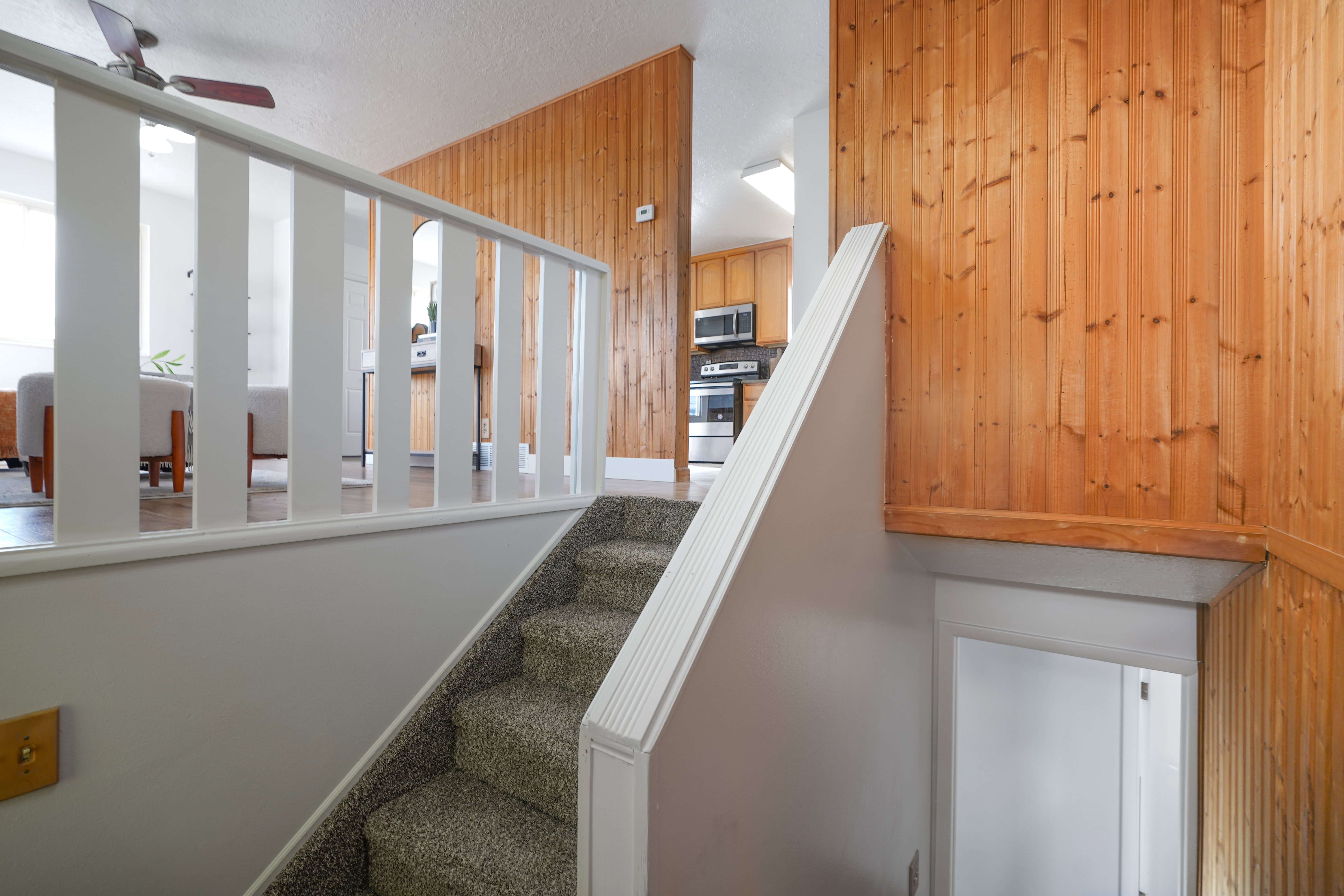 Staircase featuring a ceiling fan, a textured ceiling, and carpet flooring