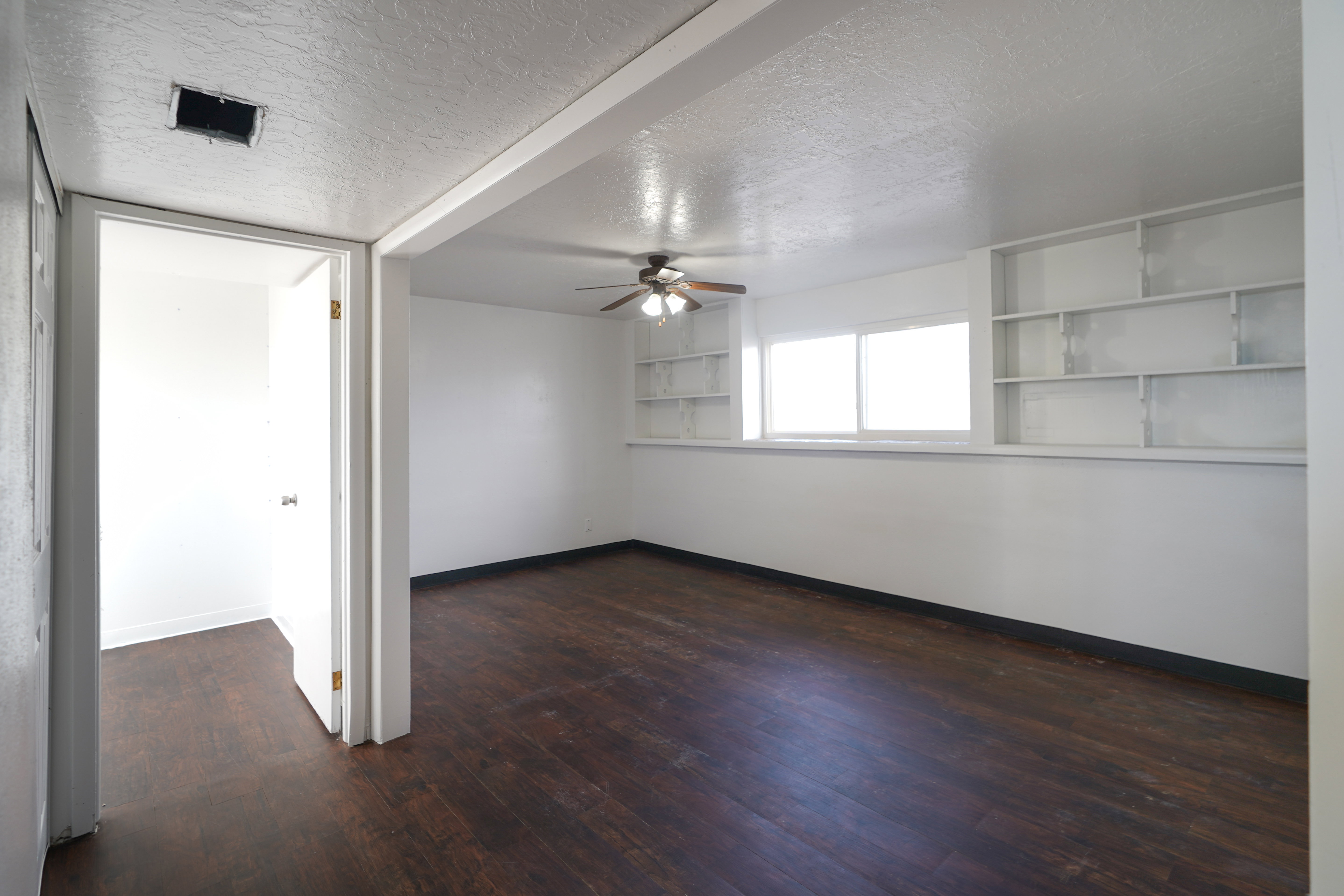 Spare room with a textured ceiling, dark wood-style floors, and a ceiling fan