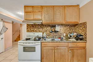 Kitchen featuring white electric stove and light wood finish cabinetry