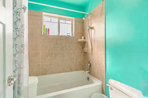 Bathroom featuring toilet and shower / tub combo with curtain