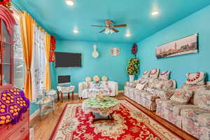 Living room with wood finished floors, ceiling fan, and recessed lighting