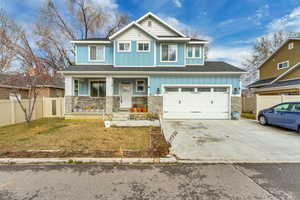 Craftsman-style home featuring board and batten siding, covered porch, stone siding, driveway, and an attached garage