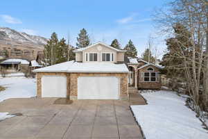 View of front facade featuring stone siding, driveway, and an attached garage