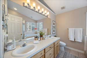Full bathroom featuring lofted ceiling, double vanity, a garden tub, and light tile patterned floors