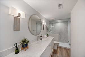 Full bathroom featuring vanity, a marble finish shower, and light wood-type flooring