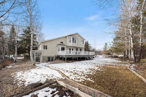 Snow covered house featuring a deck and a vegetable garden