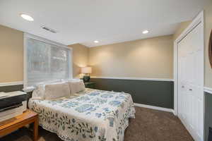 Bedroom with dark carpet, a closet, and recessed lighting
