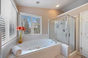 Full bathroom featuring a shower stall, a jetted tub, and lofted ceiling