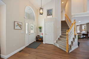 Foyer with dark wood-style floors, lofted ceiling, and suspended lighting