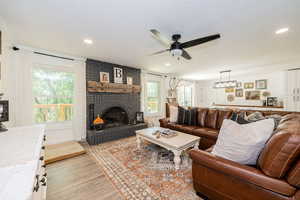 Living room featuring a fireplace, light wood-style floors, and ceiling fan