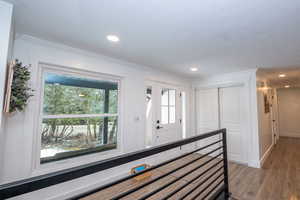 Hallway with light wood-type flooring, recessed lighting, and crown molding