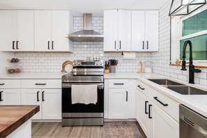 Kitchen featuring stainless steel appliances, white cabinets, butcher block counters, light wood-style flooring, and backsplash