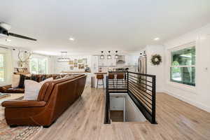 Living room featuring light wood-type flooring, a ceiling fan, and recessed lighting