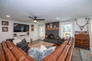 Living area featuring wood finished floors, ceiling fan, and a fireplace