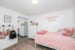 Bedroom featuring a closet, wood finished floors, and a textured ceiling