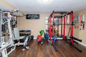 Exercise room with dark wood-style flooring and a textured ceiling