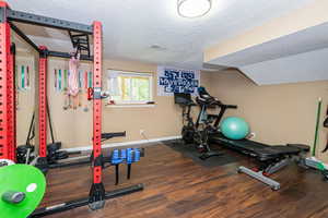 Exercise room featuring dark wood-style floors and a textured ceiling