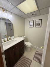 Bathroom featuring vanity, a paneled ceiling, light tile patterned flooring, and a shower