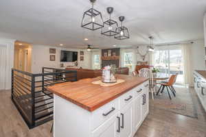 Kitchen featuring butcher block counters, white cabinets, a center island, open floor plan, and pendant lighting