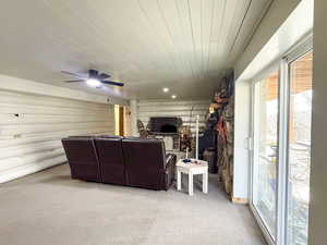 Living room featuring a ceiling fan, light colored carpet, log walls, and wood ceiling