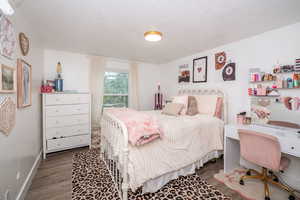 Bedroom with wood finished floors and an office area