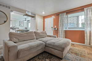 Living room with ceiling fan, a textured ceiling, wood finished floors, and recessed lighting