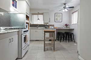 Kitchen with gas range gas stove, white cabinetry, a kitchen breakfast bar, and light tile patterned flooring