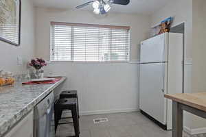 Kitchen with freestanding refrigerator, a wainscoted wall, wood counters, stainless steel dishwasher, and a ceiling fan
