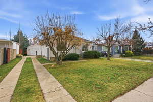 View of front of home with a garage, concrete driveway, and an outbuilding