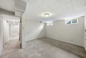 Basement with light colored carpet and baseboards