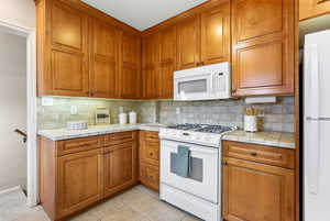 Kitchen with tile counters, white appliances, wood finish cabinetry, and light tile patterned floors